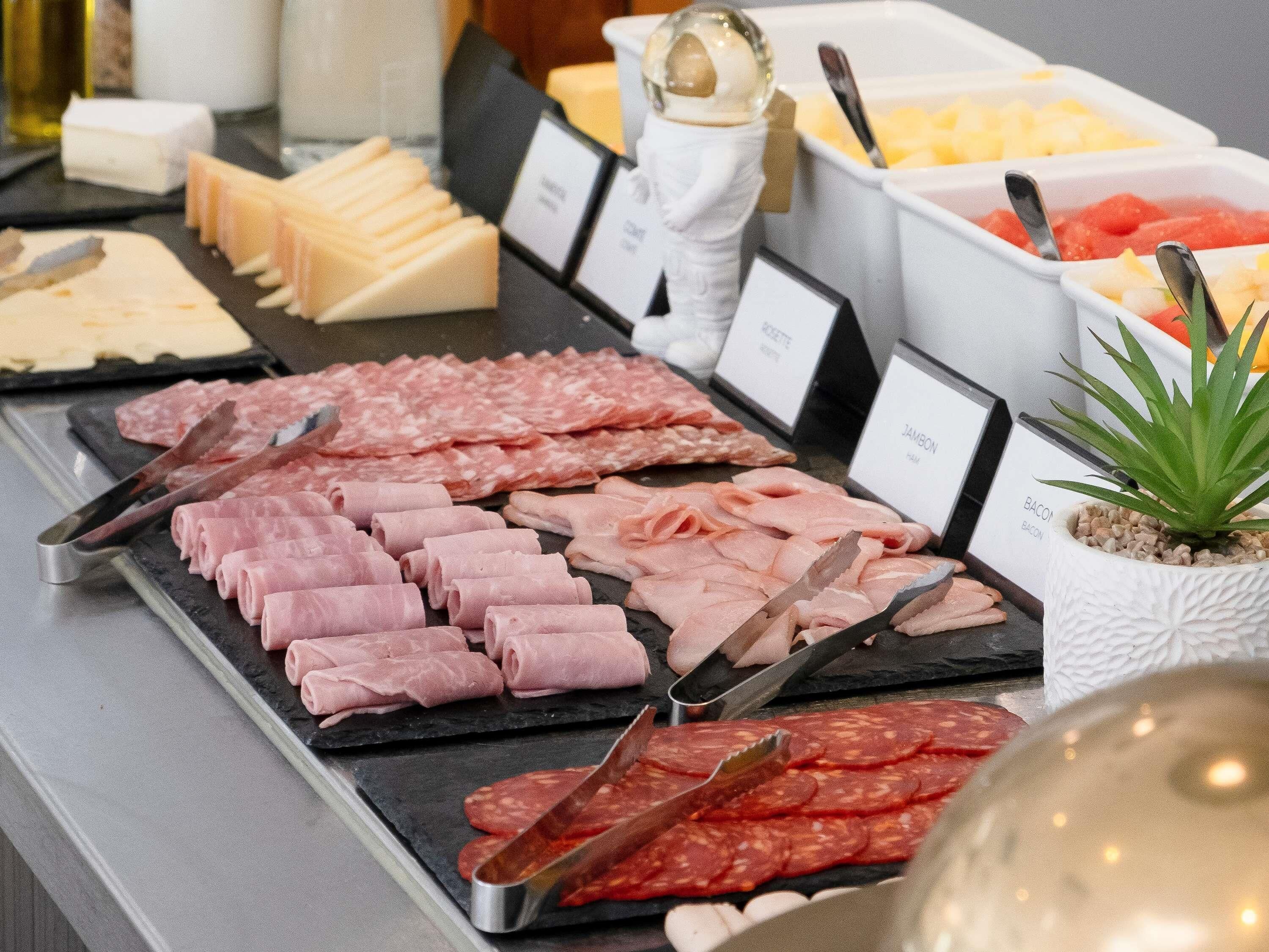 A variety of meats and cheeses on display, including ham, salami, and different types of cheese.