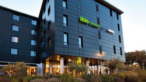 Een modern hotel met een plat dak, grote ramen en een bordje met de tekst 'ibis Styles Hotel'.