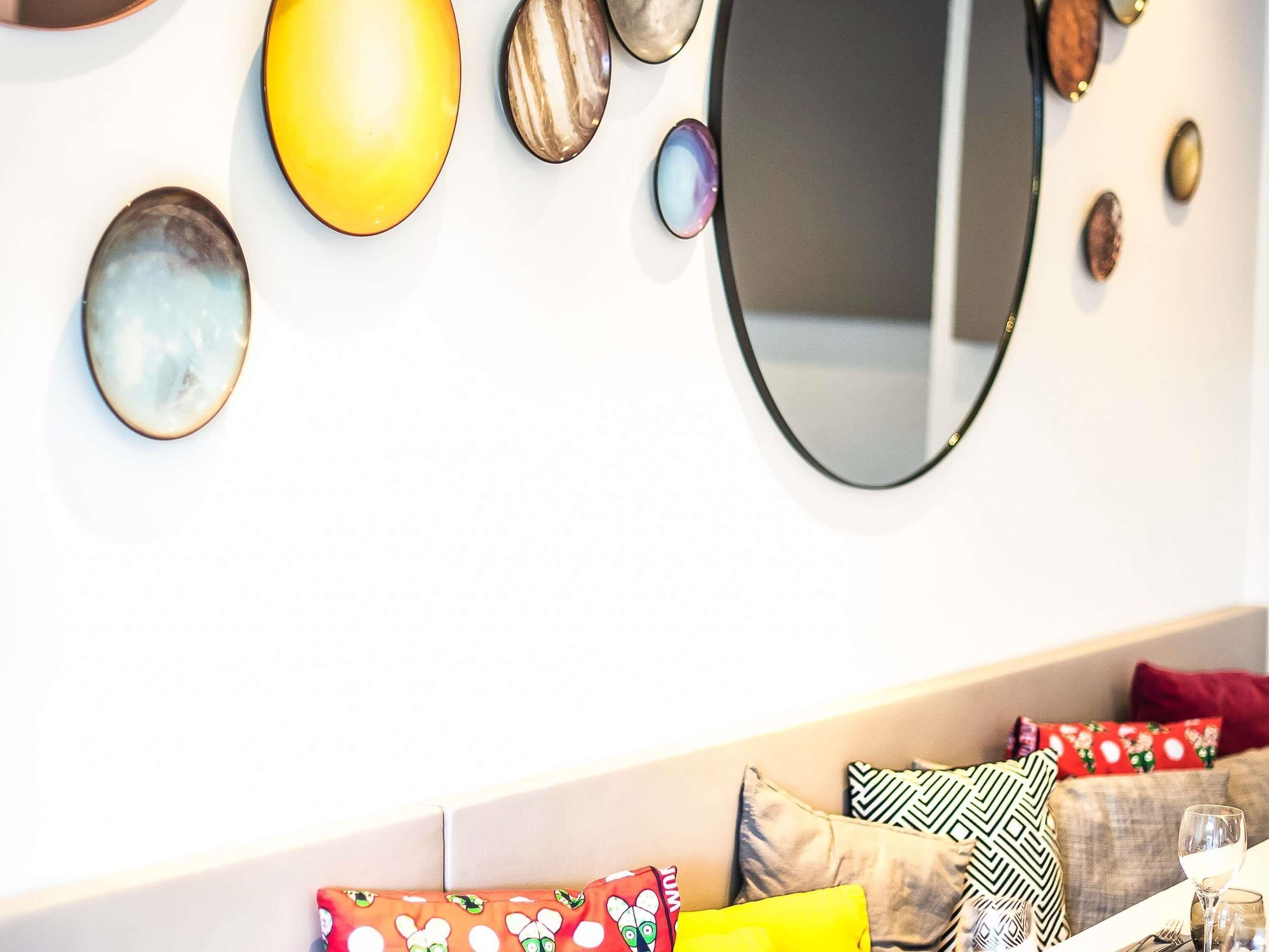 Zona pranzo con tavolo bianco, uno specchio e diversi oggetti decorativi appesi al muro.