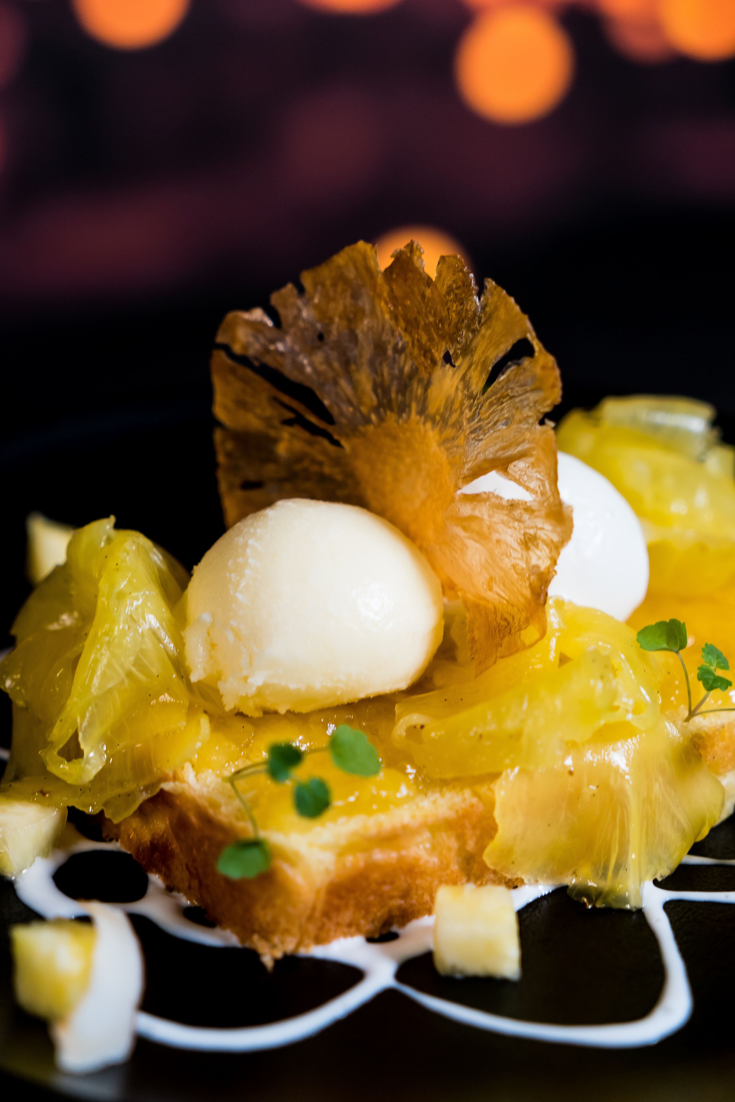 A dessert with a golden crust, a white scoop, and a decorative leaf on a plate.
