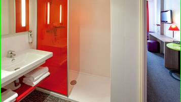 A modern bathroom with a white sink, red accents, and a glass shower enclosure.