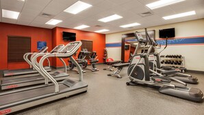 Un gimnasio con cintas de correr, elípticas y máquinas de pesas.