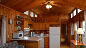 A wooden cabin interior with a kitchen, dining area, and a ceiling fan. - Black Walnut Point Inn (Tilghman)