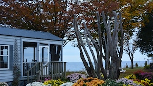 A coastal house with a wooden deck and a garden with colorful flowers. - Black Walnut Point Inn (Tilghman)