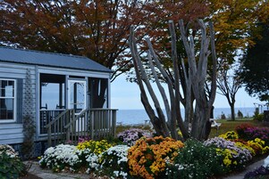 A coastal house with a wooden deck and a garden with colorful flowers.