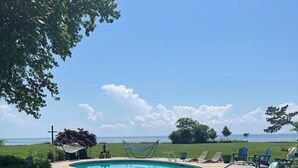 A swimming pool with blue chairs, a hammock, and a view of the ocean. - Black Walnut Point Inn (Tilghman)