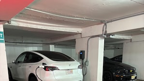 A parking garage with two cars, one white and one black, parked under a red awning. - Aztec Ocean Resort (Seaside Heights)