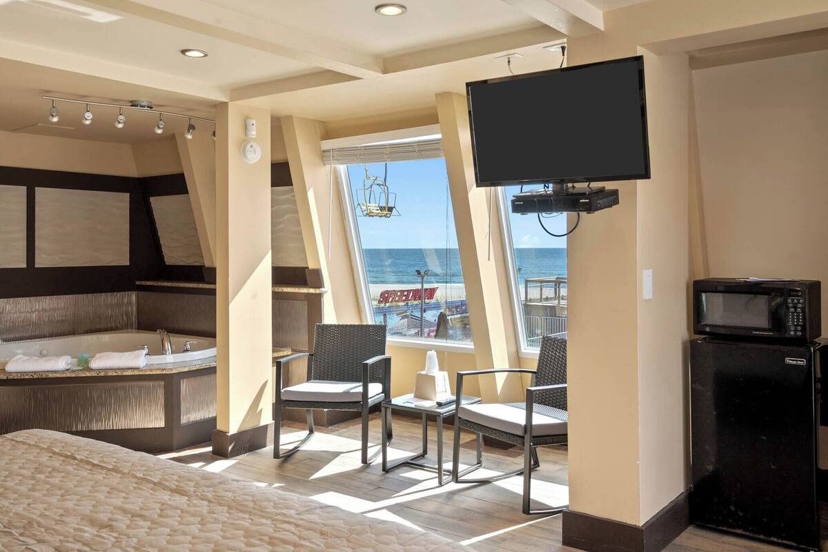 A room with a bed, a TV, a microwave, and a view of the sea.