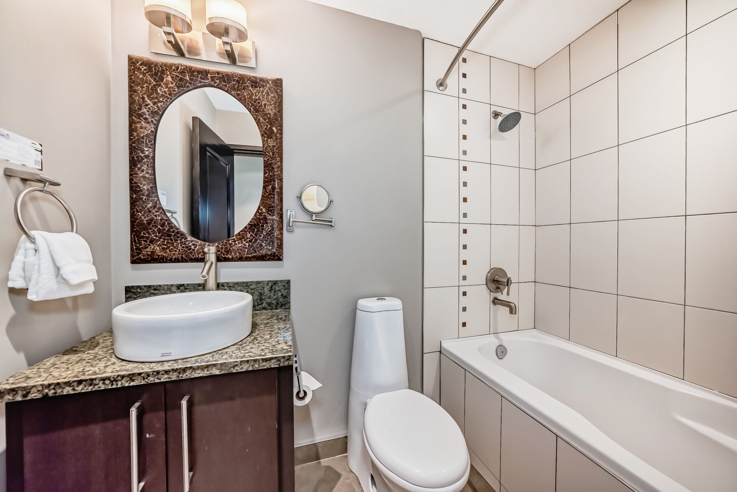 A modern bathroom with a large sink, a mirror, a toilet, and a bathtub.