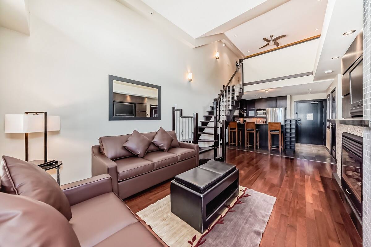 A modern living room with a brown leather sofa, a black coffee table, and a fireplace.