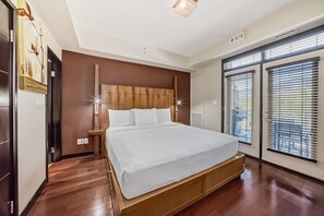 A bedroom with a large bed, wooden headboard, and a view through floor-to-ceiling windows.