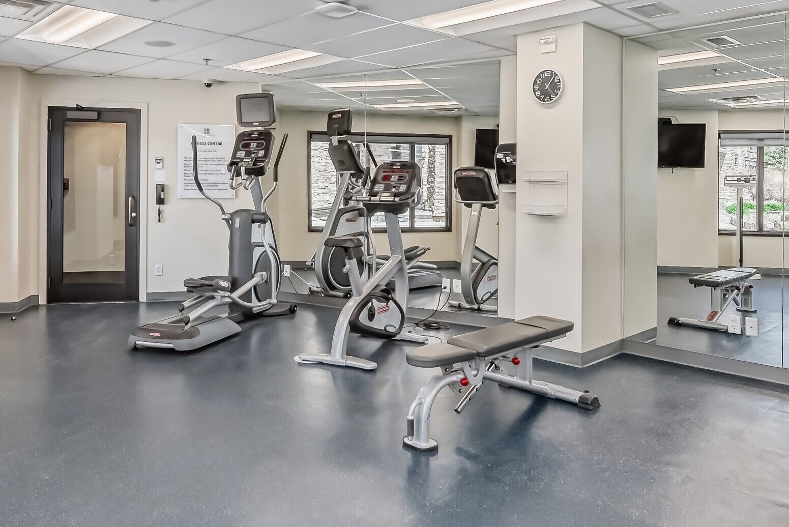 A fitness center with treadmills, elliptical machines, and a weight bench.