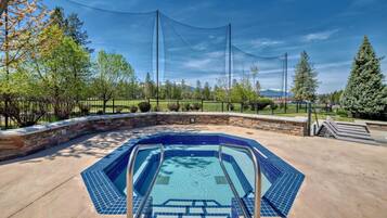 Una piscina con revestimiento de azulejos azules, rodeada por un muro de piedra y barandillas de metal.
