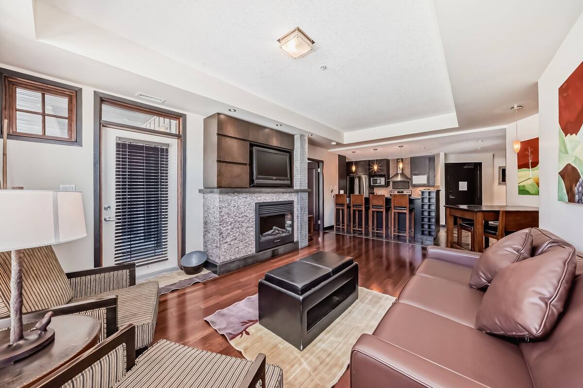 A modern living room with a fireplace, a sofa, and a dining area with a table and chairs.