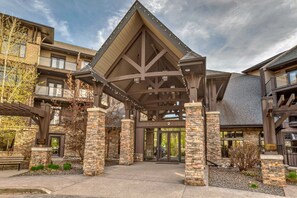 A building with a covered entrance, stone pillars, and a sign indicating it is a hotel. - Copper Point Resort (Invermere)