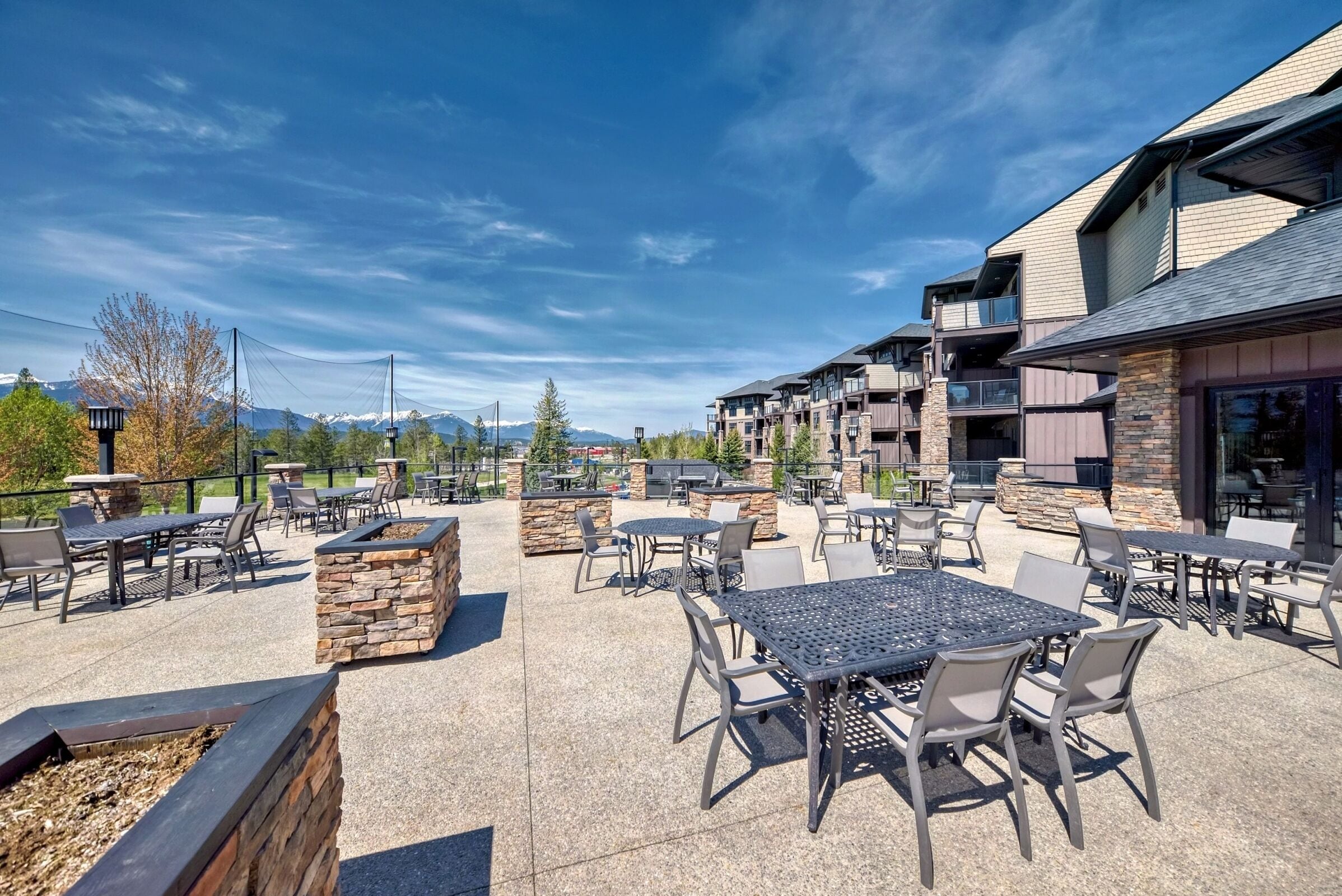 An outdoor patio area with tables and chairs, stone planters, and a view of mountains.