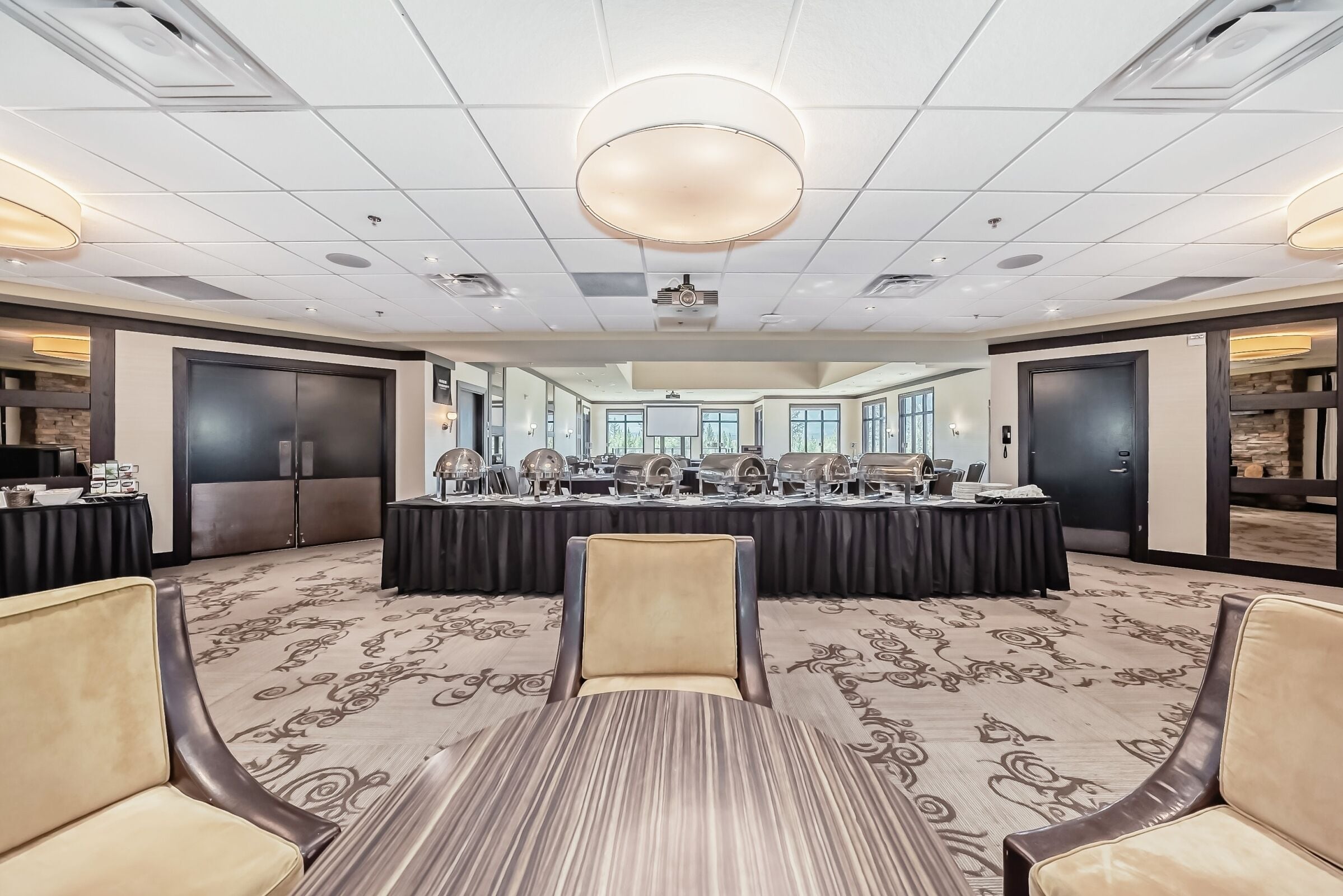 A conference room with a large table, chairs, and a carpeted floor.