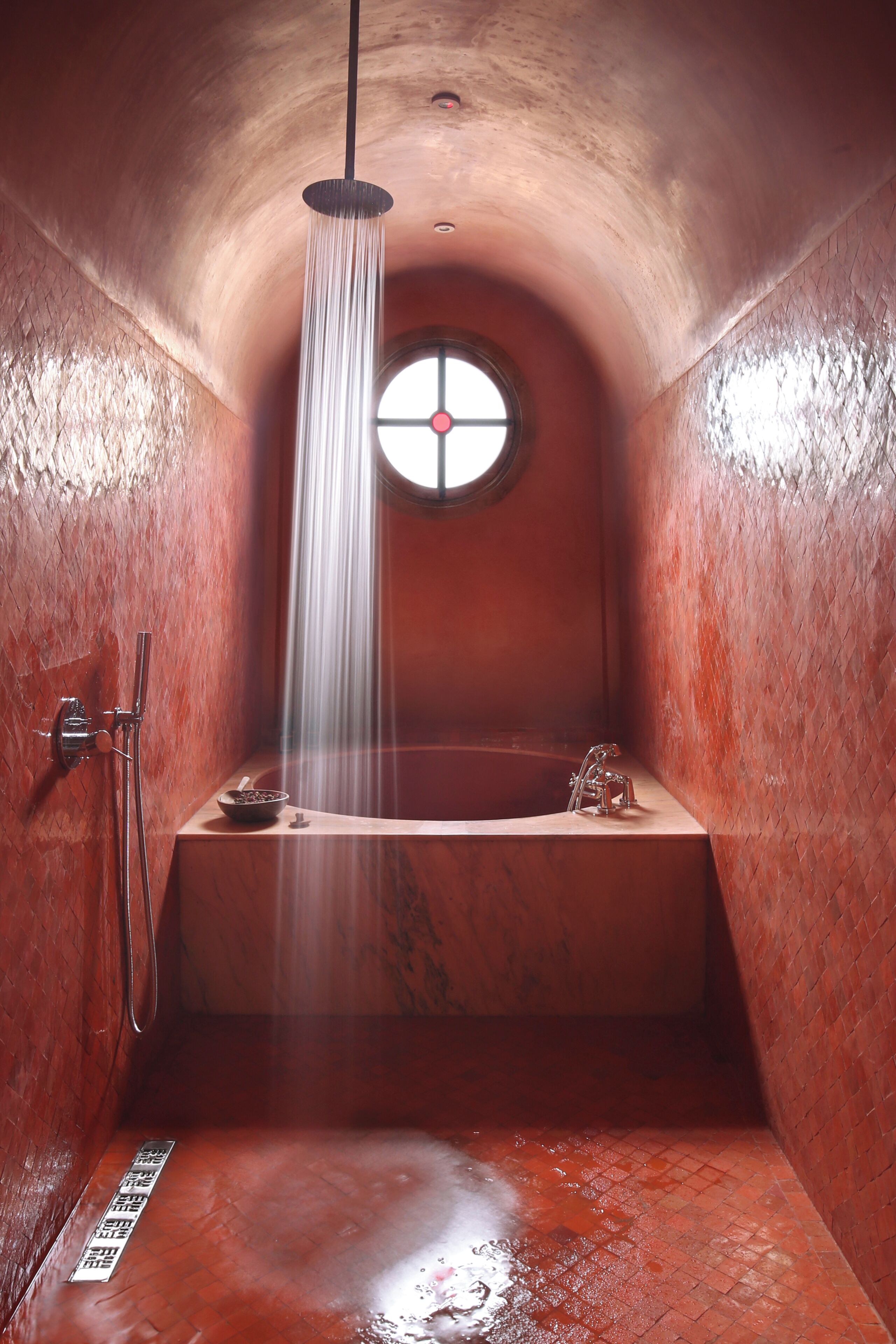 A small, enclosed bathroom with a bathtub, a showerhead, and a window.