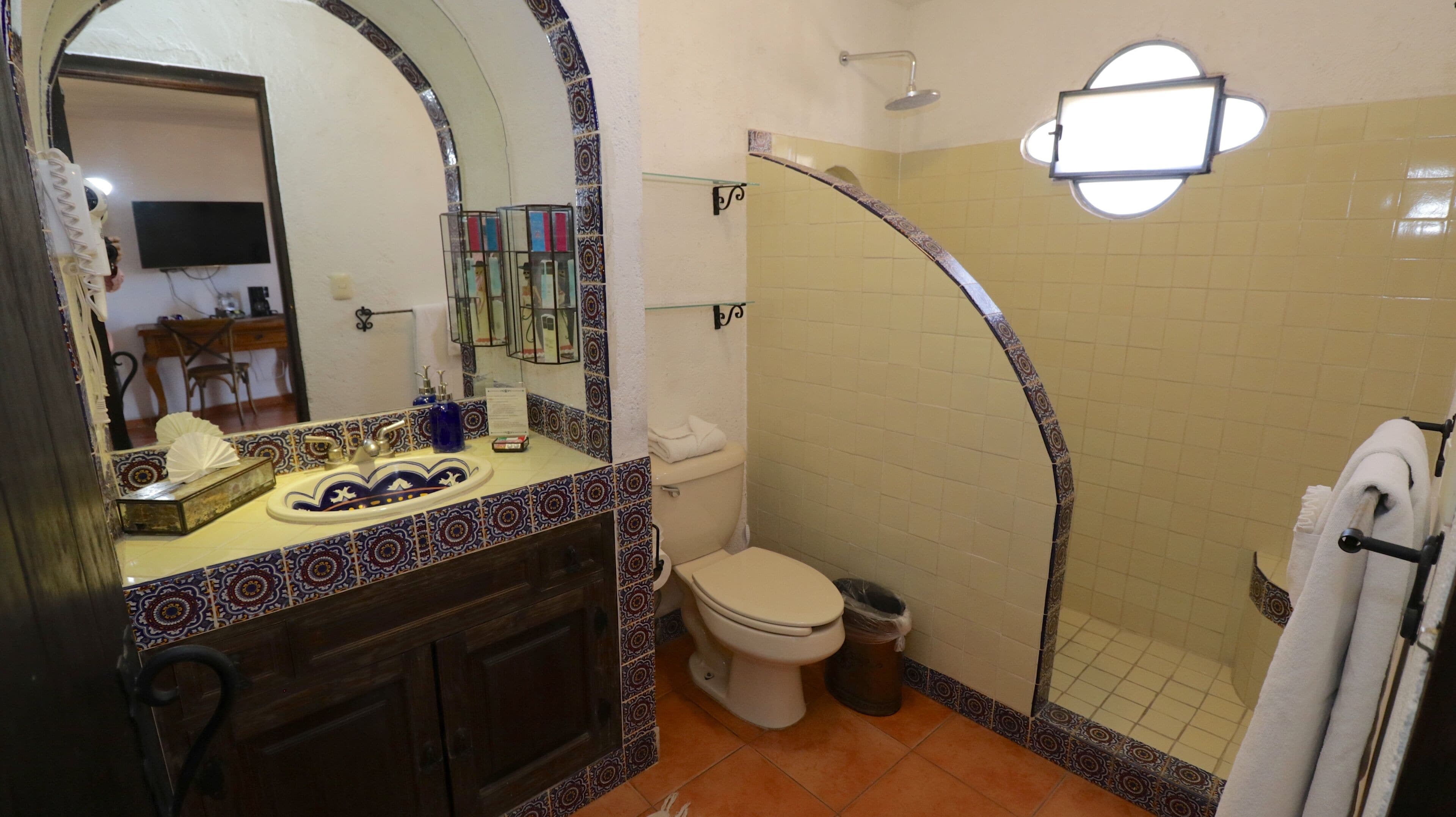 A bathroom with a tiled shower, a toilet, and a sink with a mirror.
