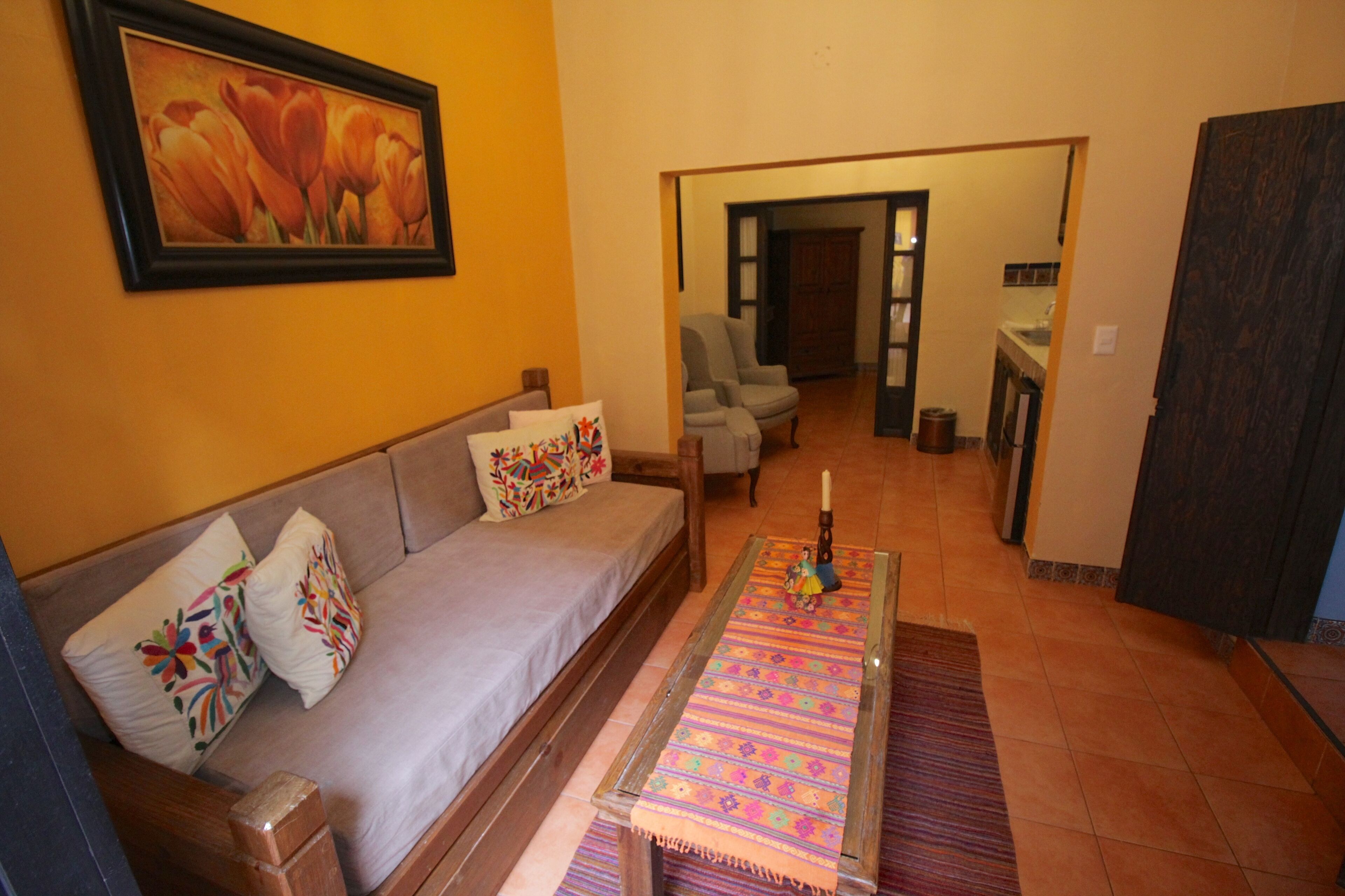 A living room with a sofa, colorful pillows, a coffee table, and a painting on the wall.