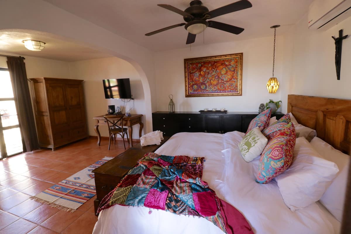 Une chambre à coucher avec un lit, un bureau, une chaise et un ventilateur de plafond.