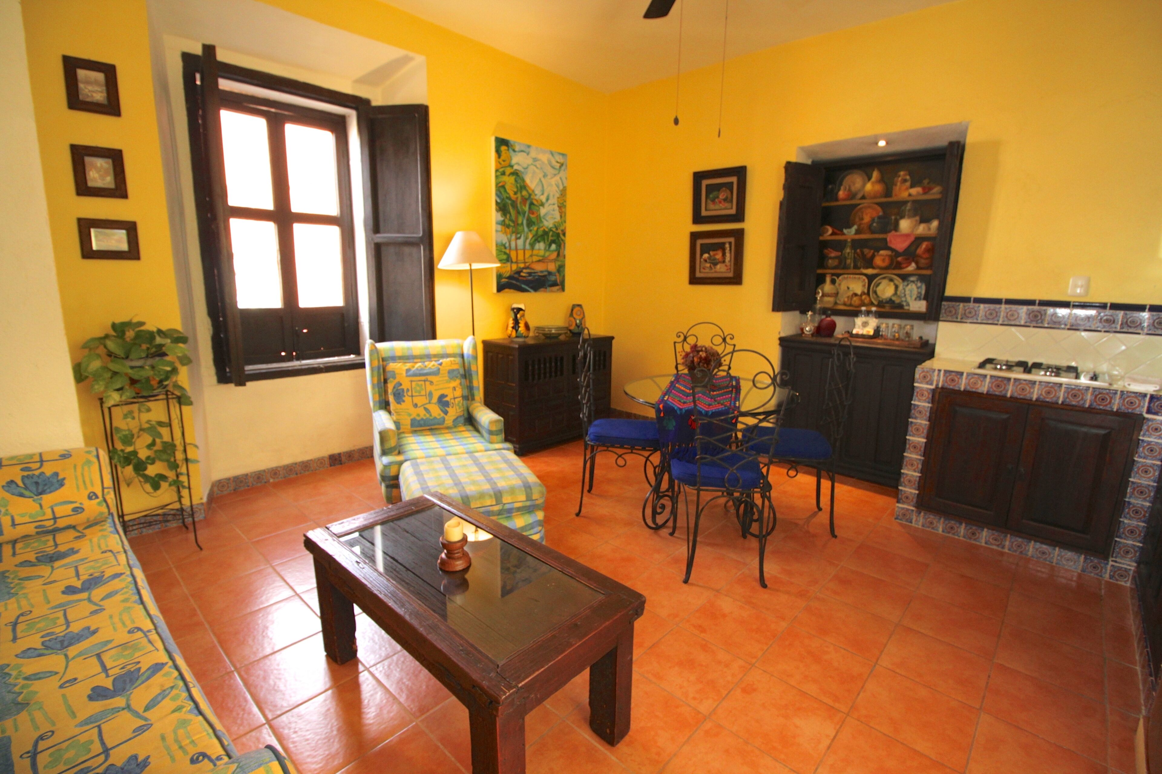 A living room with a sofa, armchairs, a coffee table, and a dining area with chairs and a cabinet.