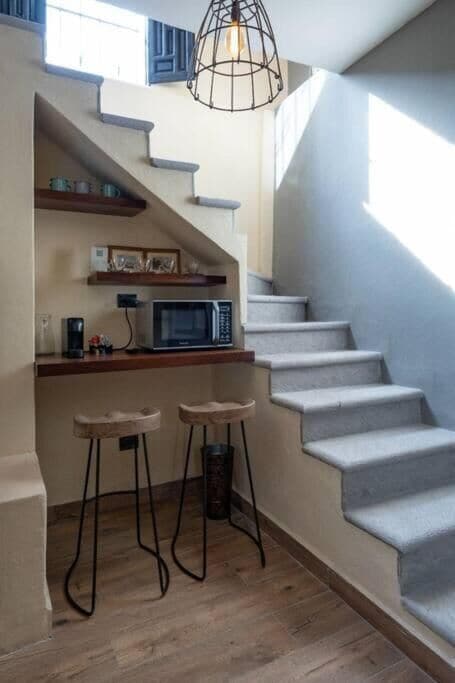 Eine Treppe mit integrierter Küchenzeile, inklusive Mikrowelle, Sitzgelegenheiten und einer Pendelleuchte.