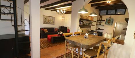 Un espacio acogedor con mesa y sillas de madera, un sofá y una escalera.