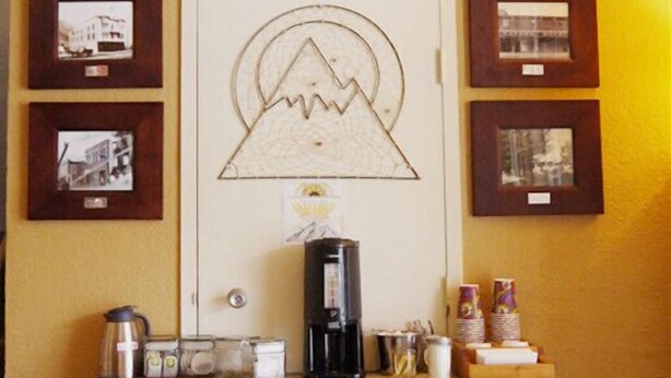 Une petite cuisine équipée d’une machine à café, de tasses et d’une poubelle.