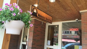L’extérieur de l’hôtel Mountain Hound Inn, avec un jardinier suspendu et une pancarte indiquant « CHAMBRES LIBRES ».