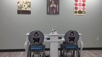 A dining area with two chairs featuring bear designs, a white table, and three framed artworks on the wall.