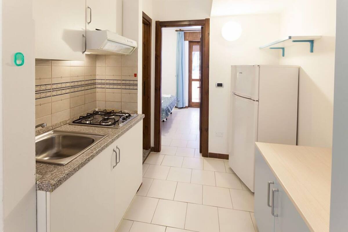 Una cucina piccola con piano cottura a gas, lavello e frigorifero.
