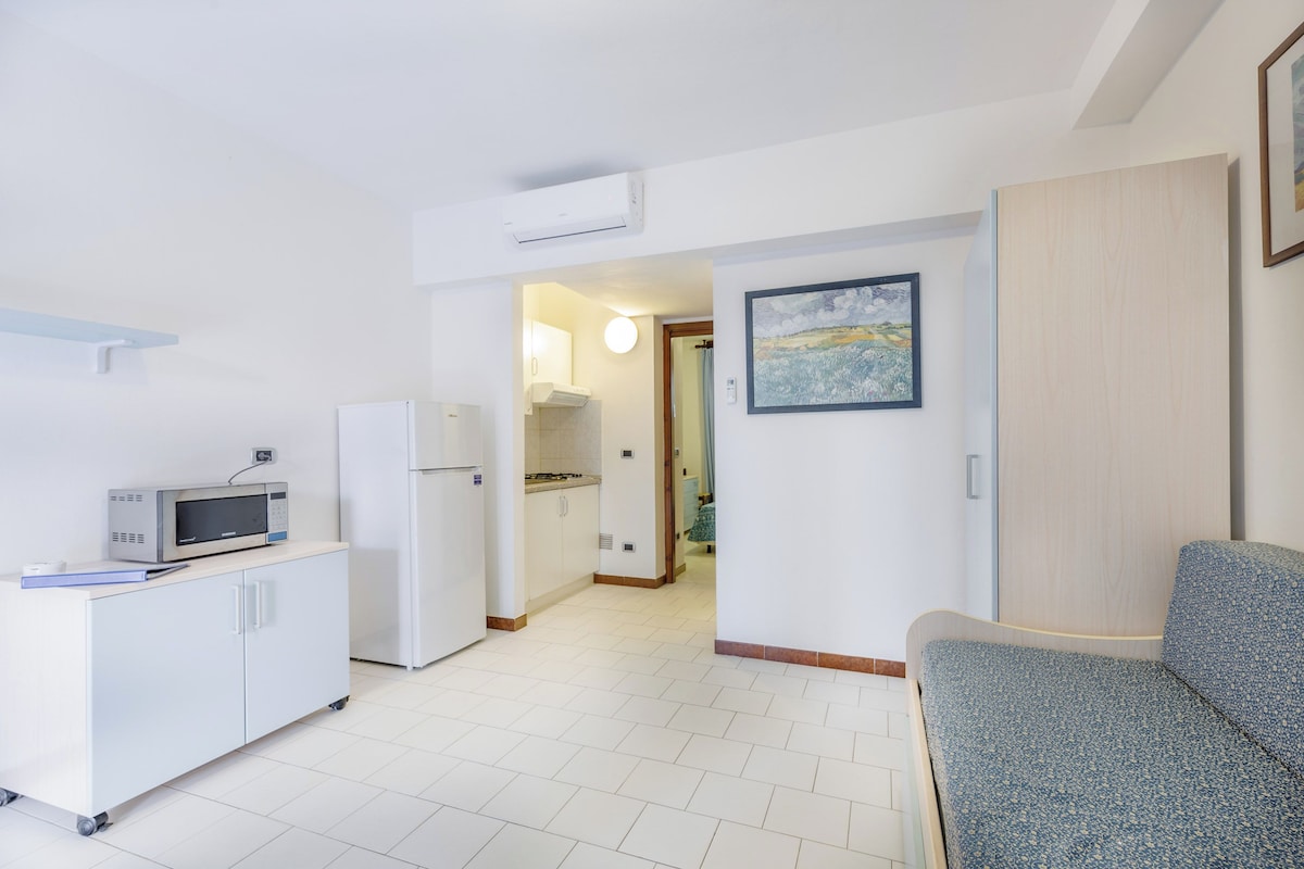 A compact kitchen with a microwave, refrigerator, and a small dining area.