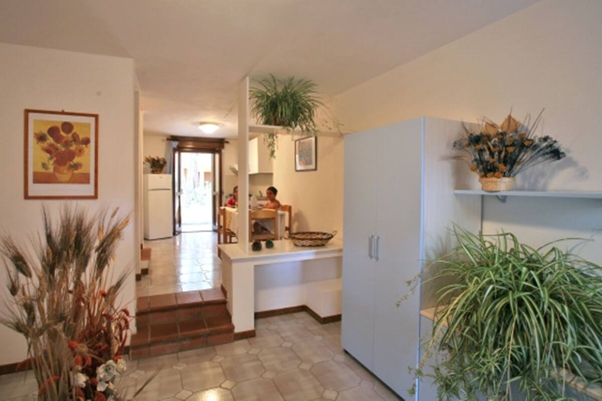 Un'ampia cucina con isola centrale, un'area pranzo con tavolo e sedie, e un corridoio che conduce a un soggiorno.