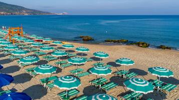 Playa privada, playa de arena negra, camastros y sombrillas