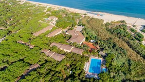 Luftaufnahme eines Anwesens an der Küste mit Schwimmbad, Strandzugang und üppiger Vegetation.