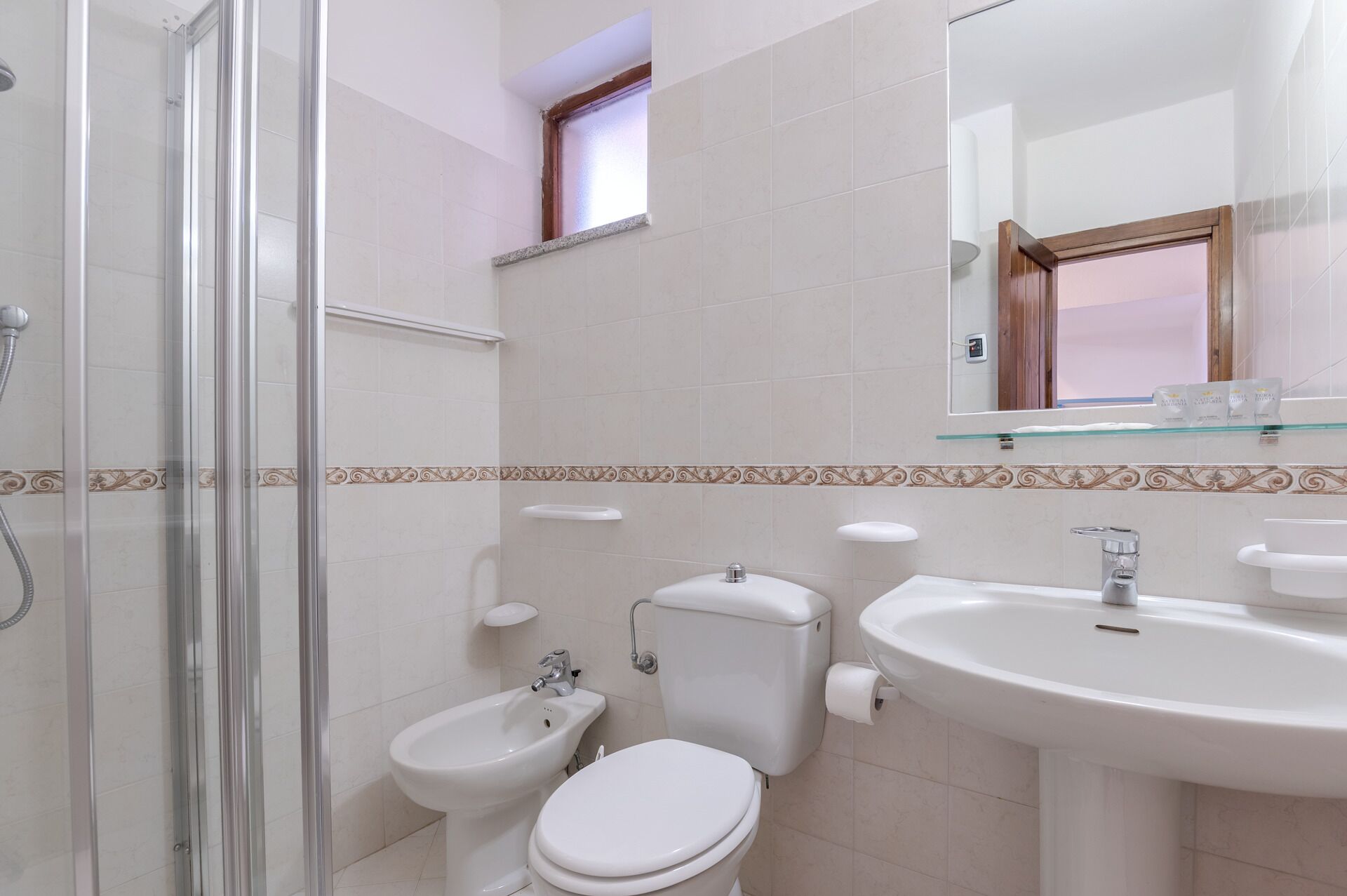 Ein Badezimmer mit Dusche, Bidet, Toilette, Waschbecken und einem Spiegel über dem Waschbecken.