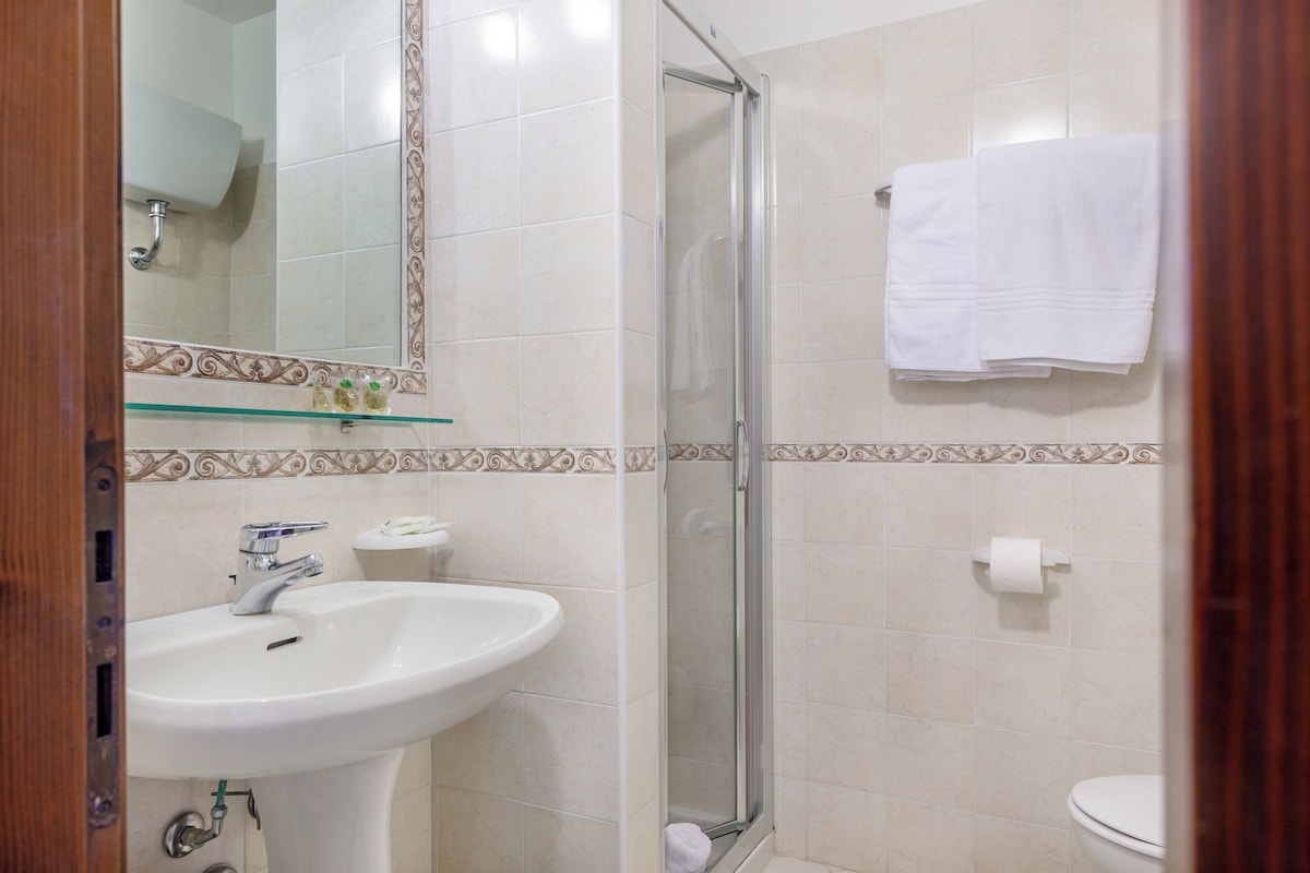 A bathroom with a sink, mirror, shower, and toilet.