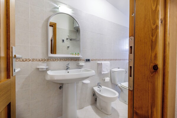 A bathroom with a sink, bidet, toilet, and mirror.