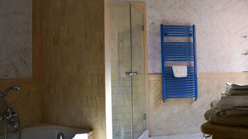 A bathroom with a bathtub, a glass-enclosed shower, and a blue towel rack.