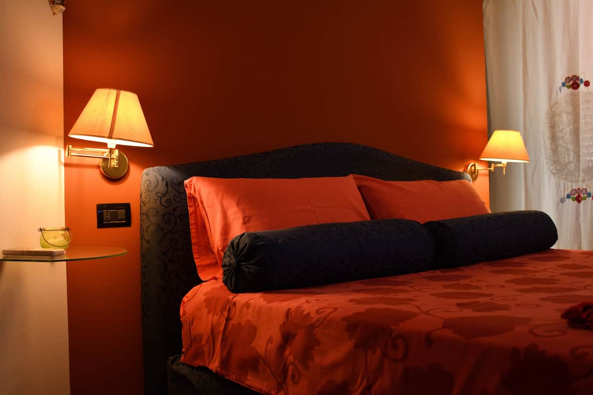 Ein Hotelzimmer mit einem großen Bett, zwei Wandleuchten und einer Glasablage mit einem kleinen Gegenstand.