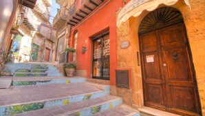 A narrow street with a building featuring a wooden door and a sign above it. - Le Casette di Lù (Agrigento)