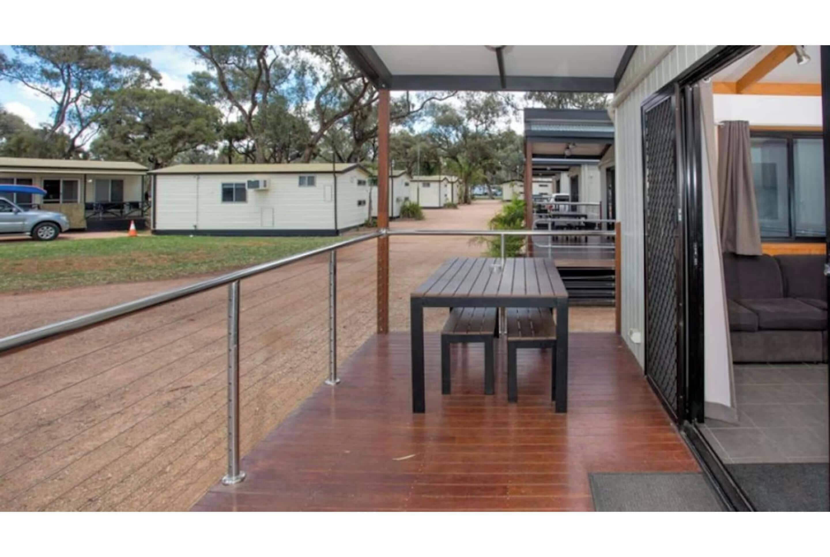 A covered outdoor area with a wooden deck, metal railing, and a table.