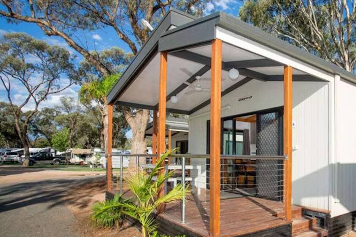 Una casa móvil moderna con porche cubierto, ventanas amplias y un área exterior cercada.