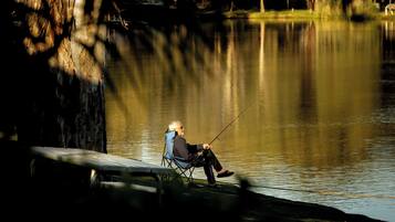 A person sitting on a chair by a calm lake, fishing.