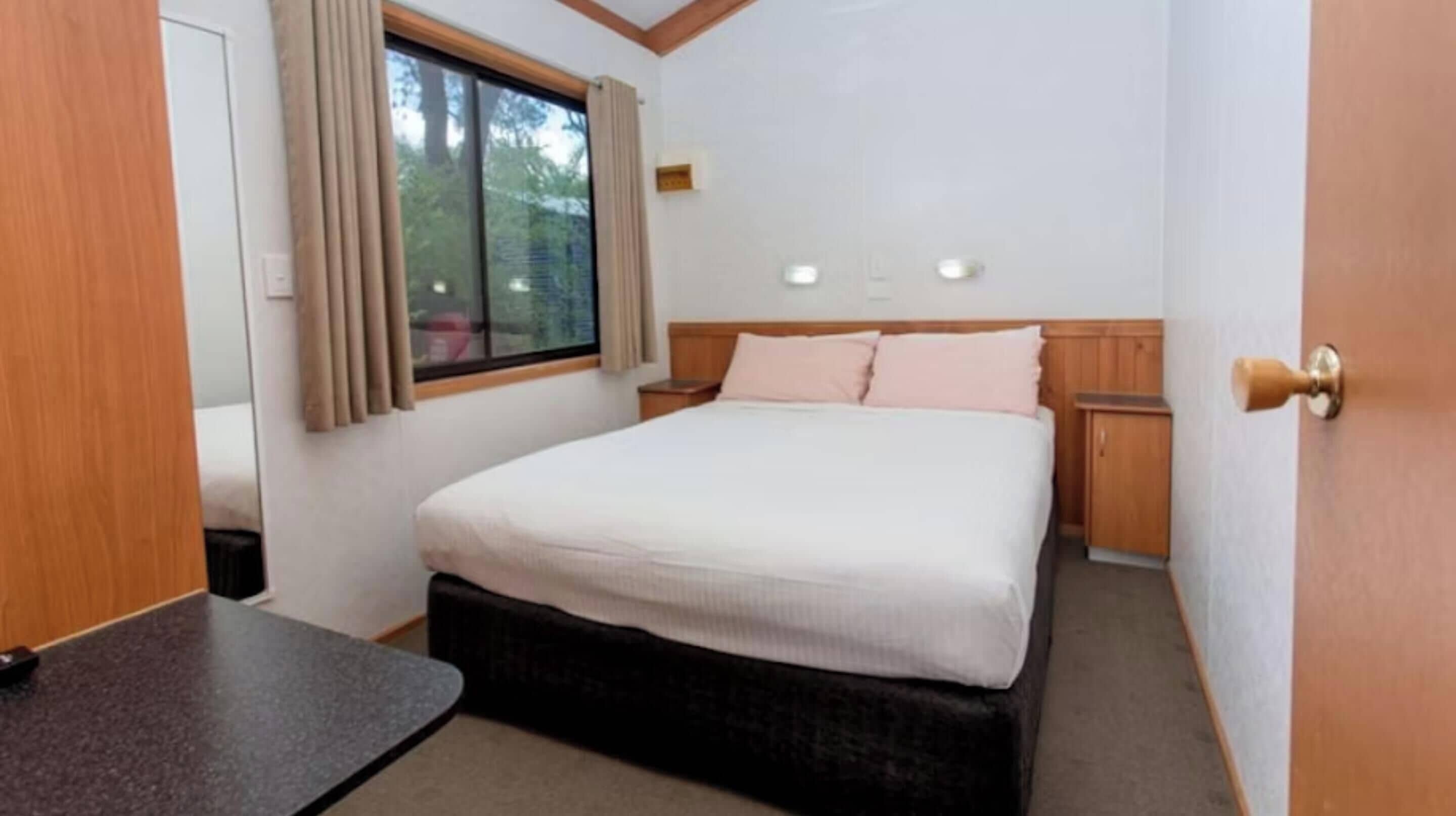 Una camera da letto con un letto, comodini, una finestra con tende e una porta.
