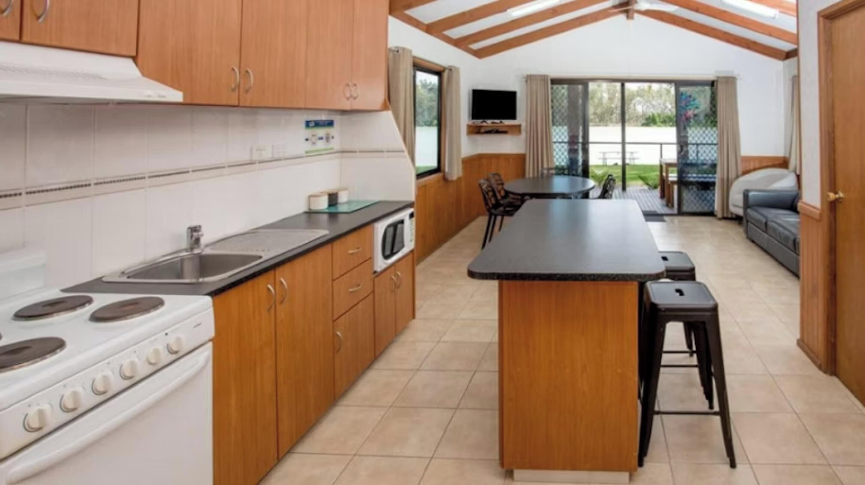 A kitchen with wooden cabinets, a stove, and a dining area with a table and chairs.