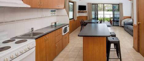 A kitchen with wooden cabinets, a stove, and a dining area with a table and chairs.