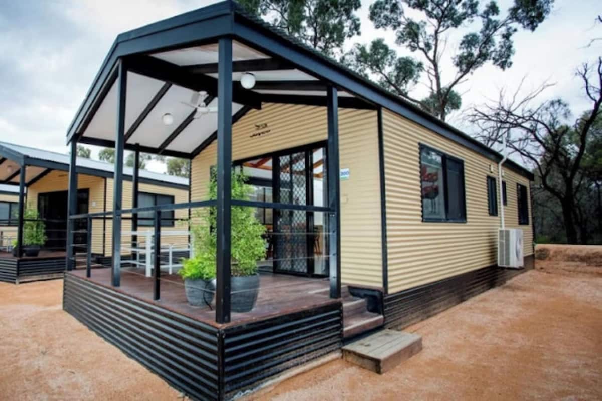 Una casa móvil moderna con un porche cubierto y un pequeño jardín.