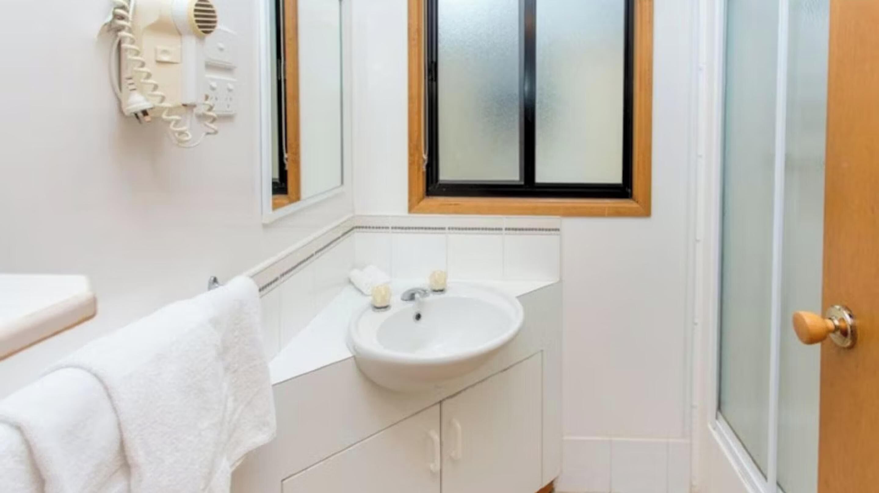 Un baño con un lavamanos blanco, un espejo y una toalla colgada en la pared.